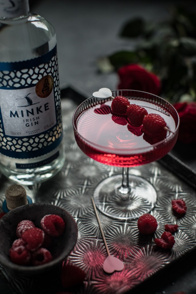 red colored cocktail with raspberries