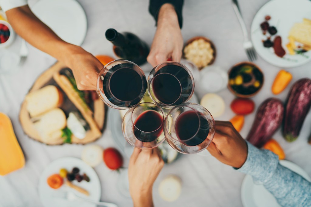 four hands toasting red wine