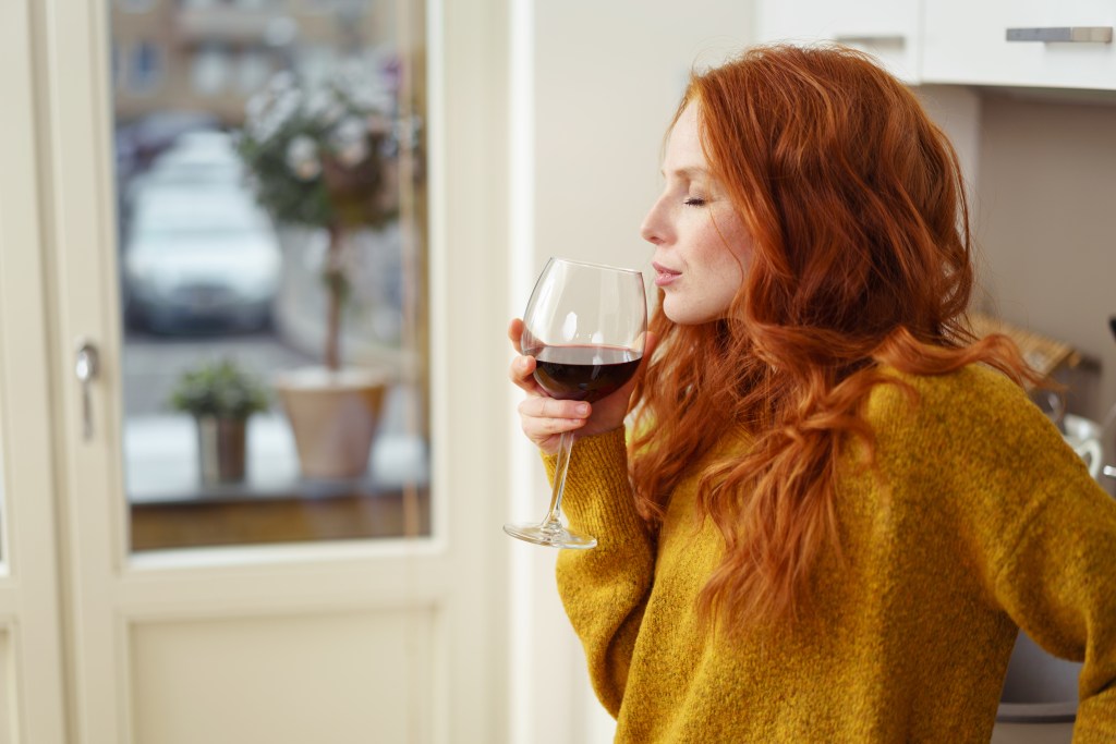 woman smelling a red wine in glass